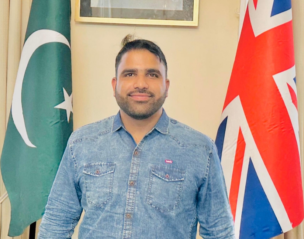 Umar standing in front of Pakistan and UK flags